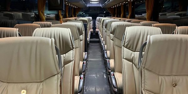 Interior of an empty coach bus with beige seats.