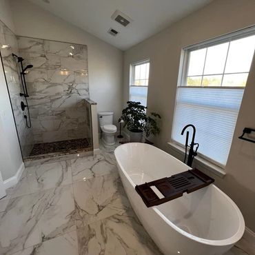 Modern bathroom with marble tiles, a freestanding bathtub, and a walk-in shower.
