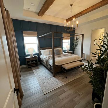 Cozy bedroom with wood beams, canopy bed, and elegant chandelier.