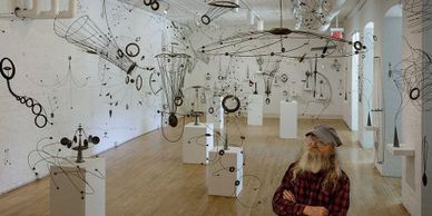 William Brady Jr. poses in his exhibition of kinetic tin sculptures.