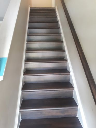 Dark wooden stairs with white walls and handrail on the right.