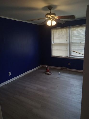 Empty room with dark blue walls, gray floor, and ceiling fan light.
