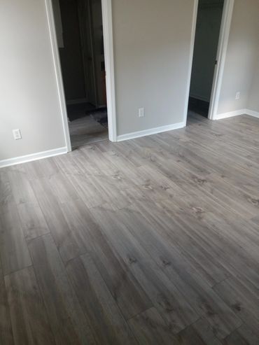 Empty room with light gray wood flooring and white walls.
