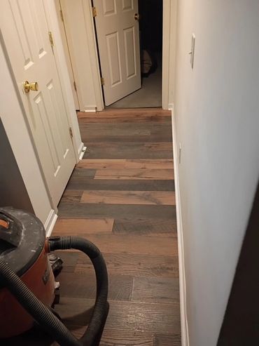 Hallway with wood flooring and vacuum cleaner in the corner.