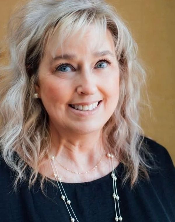 Smiling woman with blonde hair in black top.