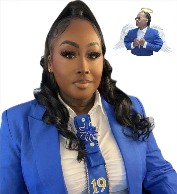 Woman in blue suit with commemorative ribbon and an angelic figure in the background.