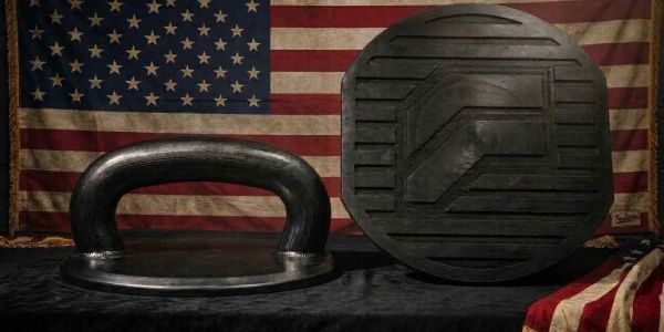 Two black fitness weights with an American flag background.