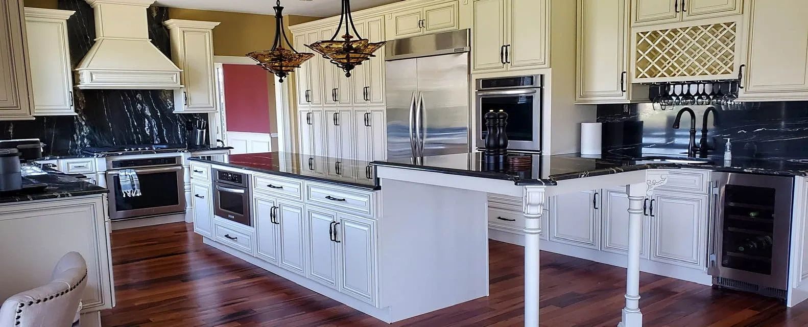 A spacious, upscale kitchen featuring two-toned cabinetry, black granite countertops and backsplash,