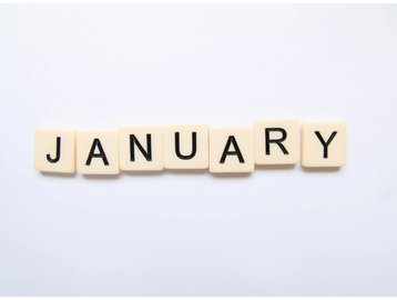 The word January spelled out with letter tiles on a white surface.