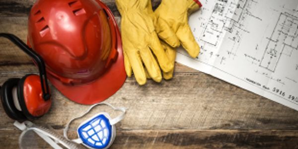 Construction safety gear and blueprints on a wooden surface.