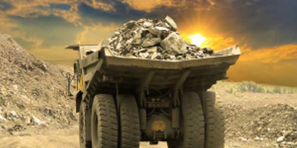 Dump truck carrying rocks at sunset.