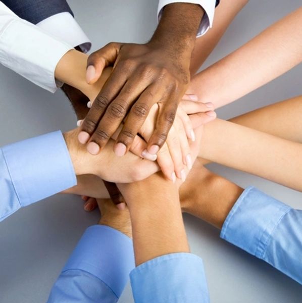 Diverse group stacking hands in a unity gesture.