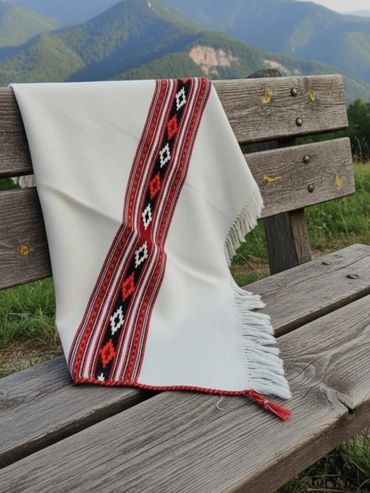 Traditional textile with red and black patterns draped over a wooden bench in the mountains.