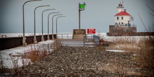Rocky pathway leading to a lighthouse with warning signs.