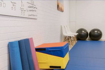 Exercise mats, chairs, and stability balls in a fitness room corner.