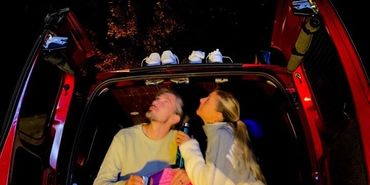 Couple sitting on the back with the rear doors open looking at the stars.