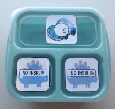A divided container with cartoon stickers labeled 'No Insulin' and a car.