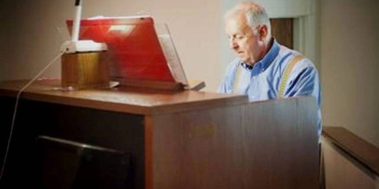 Elderly man playing piano indoors.