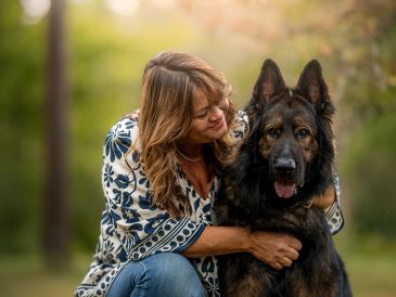 Woman embracing her large German Shepherd outdoors.