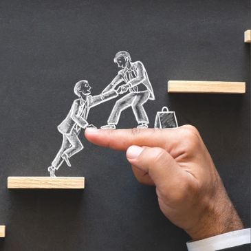 Chalkboard image of one business person helping another business person up a step which looks like a