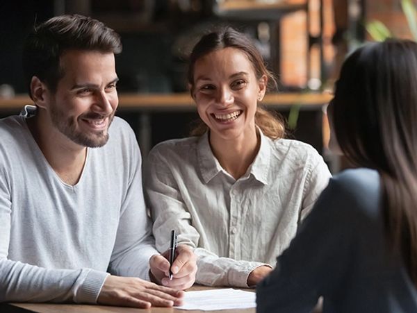 Couple happily discussing paperwork with a professional.
