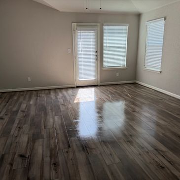 Empty room with glossy wooden floor and white blinds on windows and door.