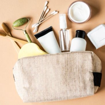 Beige toiletry bag with skincare essentials and tools.