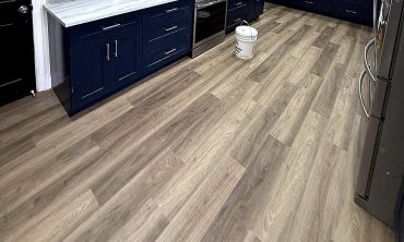Newly installed wood-patterned flooring in a modern kitchen.