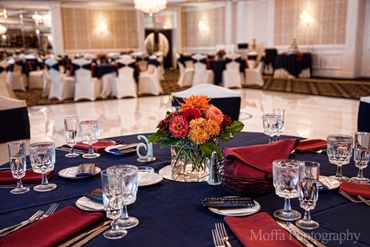 A table set with a dark blue tablecloth, wine glasses, and a floral centerpiece.
