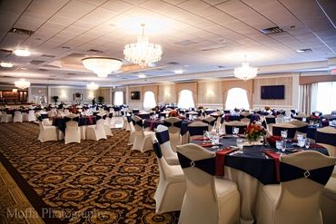 A large event space with numerous tables and chairs set for a gathering.