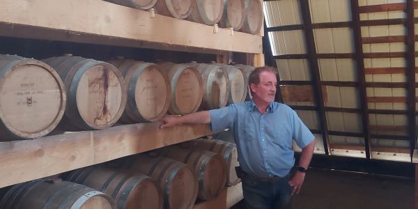 Man standing beside barrels in a warehouse.