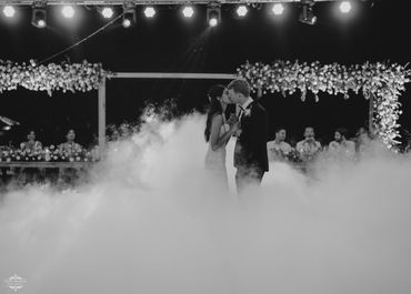 Bride and groom share a kiss on a foggy dance floor at their wedding.