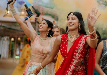 Women in traditional attire celebrating with colorful smoke.