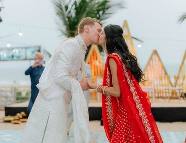 Couple sharing a kiss during a traditional outdoor wedding ceremony.