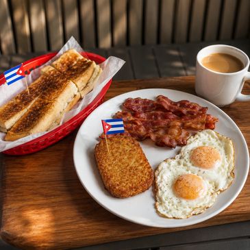 Breakfast plate with eggs, bacon, hash brown, toast, and coffee.