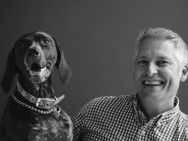 Man smiling with his dog in black and white photo.