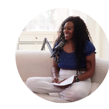 Woman podcast host smiling, sitting cross-legged with notes and microphone.