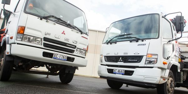 Two white Mitsubishi Fuso trucks parked side by side.