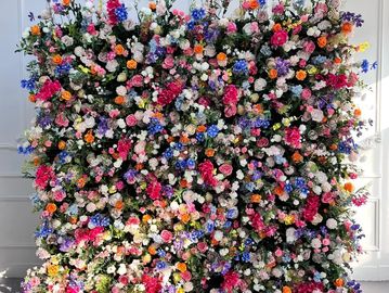 Image shows greenery backdrop with a variety of colored flowers available for rent in midland texas