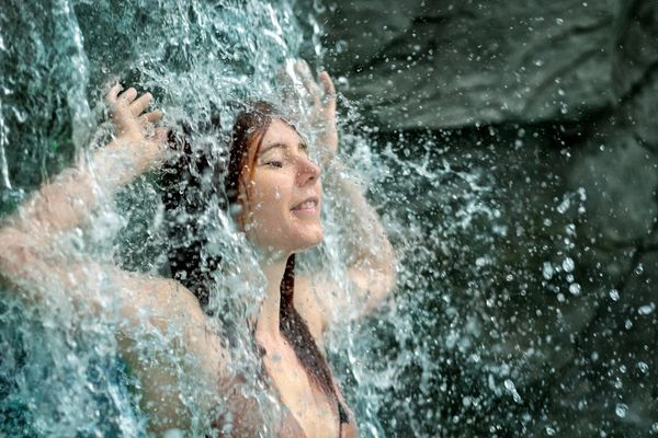 Woman enjoying the refreshing water of a waterfall.