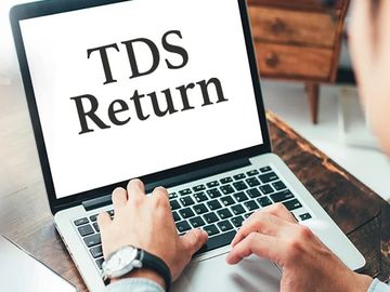 Person working on a laptop with 'TDS Return' on the screen.