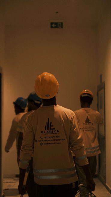 Construction workers walking in a dimly lit hallway.