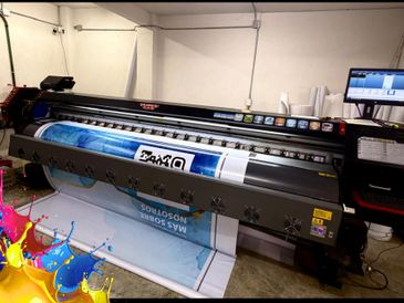 Large format printer printing a colorful banner in a workshop.