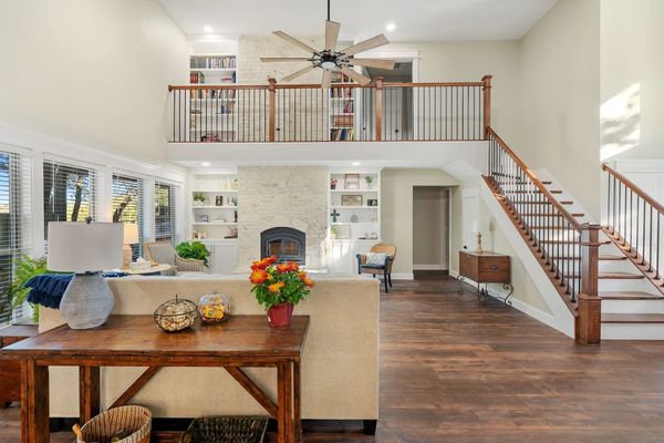 Spacious living room with wooden floors and a staircase leading to a loft area.