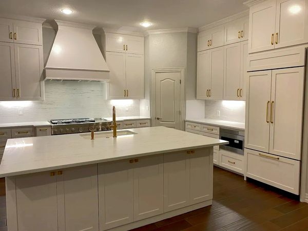 Modern kitchen with white cabinetry and gold hardware.