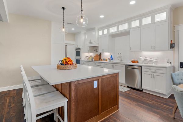 Modern kitchen with white cabinets and wooden island topped with flowers.
