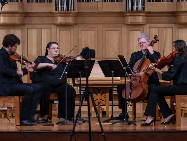 A string quartet plays music on a wooden stage.