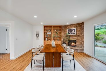 Cozy dining room with wooden table, beige chairs, and stone fireplace.