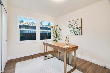 Minimalist home office with wooden desk, modern lamp, and plant.