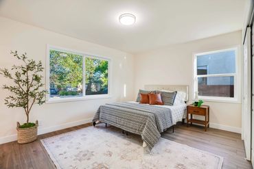 Minimalist bedroom with large windows and a patterned bedspread.